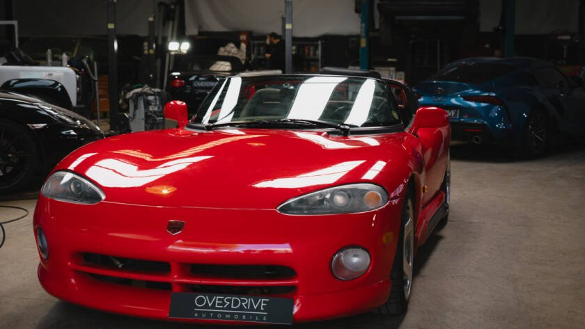 Vue avant de la Chrysler Viper RT/10 rouge, roadster américain à moteur V10, dans l'atelier Overdrive Automobile.