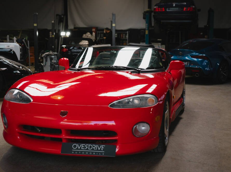 Vue avant de la Chrysler Viper RT/10 rouge, roadster américain à moteur V10, dans l'atelier Overdrive Automobile.