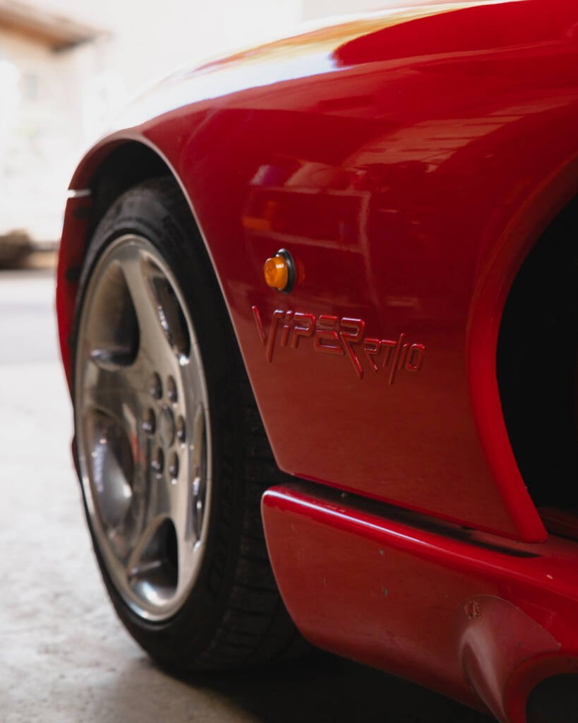 Détail de l'aile avant rouge d'une Chrysler Viper RT/10 avec son monogramme, sa jante et son échappement latéral.